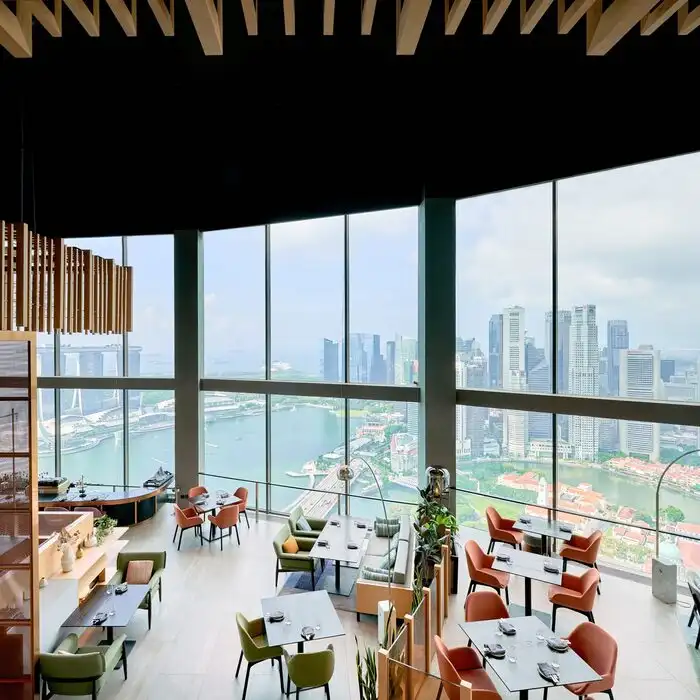 The interior of SKAI restaurant featuring modern décor and large windows overlooking Singapore